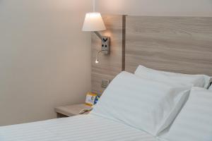 a bedroom with a white bed and a lamp at Hotel Portoconte in Porto Conte