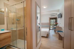 a bathroom with a glass door leading to a bedroom at Hotel Portoconte in Porto Conte