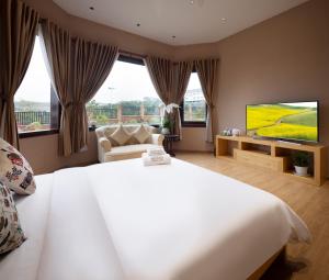 a bedroom with a large white bed and a television at Four Spring Villas & Golfs Da Lat in Da Lat