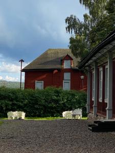 una casa rossa con due panchine davanti di Professorsvillan - hyr hela huset a Malingsbo