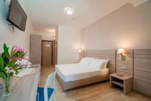 a bedroom with a bed and a table with a vase of flowers at Hotel Portoconte in Porto Conte