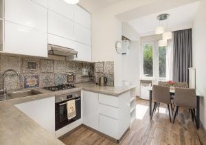 a kitchen with white cabinets and a table with chairs at HD New Apartment in Tbilisi City