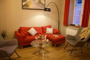 a living room with a red couch and a glass table at Maison familiale et cosy à la mer in Saint-Valery-sur-Somme
