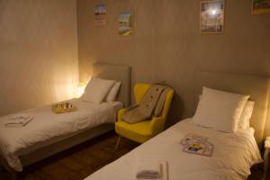 um quarto de hotel com duas camas e uma cadeira amarela em Maison familiale et cosy à la mer em Saint-Valery-sur-Somme