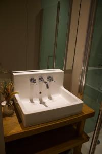 - un lavabo avec deux robinets devant un miroir dans l'établissement Maison familiale et cosy à la mer, à Saint-Valery-sur-Somme