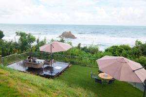 a patio with two tables and two umbrellas and the ocean at VILLA YAHACHI GARDEN in Tahara