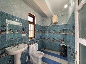 Baño de azulejos azules con aseo y lavamanos en Zu-Zu Hostels en Shimla