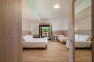 a hotel room with two beds and a balcony at Hotel Portoconte in Porto Conte