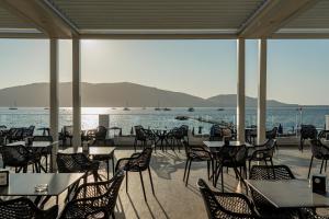 a restaurant with tables and chairs and a view of the water at Hotel Portoconte in Porto Conte