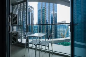 a table and chairs on a balcony with a view of the city at Cozy 1BR Apartment in Manila, BGC, with Balcony & Pool in Manila