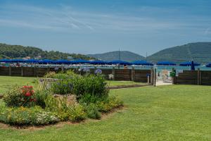 a garden with blue umbrellas and flowers in a yard at Hotel Portoconte in Porto Conte