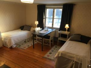 Cette chambre comprend deux lits, un bureau et une table. dans l'établissement Professorsvillan - hyr hela huset, à Malingsbo