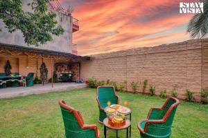 un patio con mesa y sillas en el césped en StayVista's Madan Villa - City-Center Villa with Manicured Lawn & Picturesque Sit-Outs, en Jodhpur