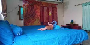 een slaapkamer met een groot blauw bed met een knuffeldier erop bij นามนโฮมสเตย์ (บ้านพ่อเสถียร) 