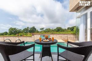 Un patio con mesa y sillas junto a una piscina. en StayVista's Coral Breeze with Plunge Pool, Games Room, Projector Setup, Proximity to Secluded Beach, en Dapoli