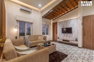 a living room with a couch and a tv at StayVista's Coral Breeze with Plunge Pool, Games Room, Projector Setup, Proximity to Secluded Beach in Kolthare