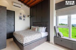 Un dormitorio con una cama grande y una ventana. en StayVista's Coral Breeze with Plunge Pool, Games Room, Projector Setup, Proximity to Secluded Beach, en Dapoli