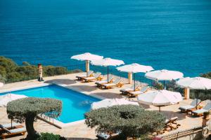- une piscine avec chaises longues et parasols et l'océan dans l'établissement Sa Pedrissa, à Deià