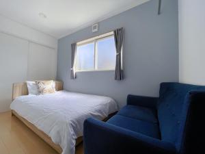1 dormitorio con 1 cama y 1 silla azul en HAKUBA House LuckyStar5 next to shuttle bus station ,711 ,restaurants Modern Chalet, en Hakuba