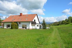 a white house with a red roof in a field at Unsere Ferienwohnung Stefan im Riesengebirge! in Dolní Lánov