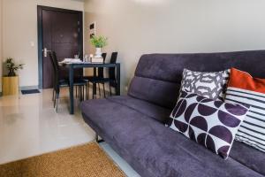 uma sala de estar com um sofá roxo e uma mesa em Cozy 1BR Apartment in Manila, BGC, with Balcony & Pool em Manila