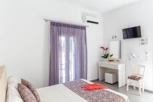a bedroom with a bed and a desk and a window at Aigli Villa in Fira