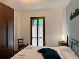 a bedroom with a bed and a chair and a window at La Corte della Casera in Cassina Valsassina