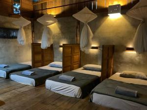 three beds in a room with wooden floors at Cabinthai in Mae Chaem