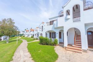 a row of white houses with a pathway at Apartamentos Son Bou Gardens By MENORCARENTALS in Son Bou