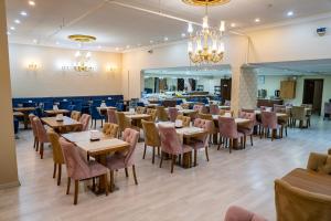 ein Esszimmer mit Tischen, Stühlen und Kronleuchtern in der Unterkunft Grand Hamit Hotel in Ankara