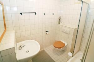 a white tiled bathroom with a toilet and a sink at Ferienwohnung Naturparadies Gnitz in Lütow +12 photos
