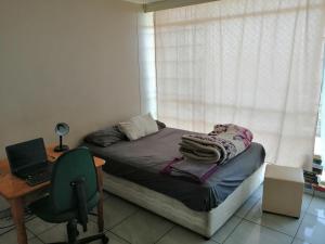 a bedroom with a bed and a desk with a laptop at Kingswood Flats in Pretoria