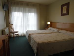 a hotel room with a bed and a chair and a window at Hotel Akelarre in Santiago de Compostela
