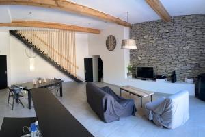 uma sala de estar com uma mesa e cadeiras e uma parede de pedra em Piscine privée sans vis à vis / Calme / Babyfoot em Conques-sur-Orbiel