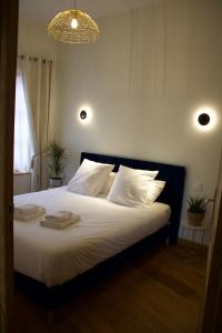 - une chambre dotée d'un lit avec des draps blancs et un lustre dans l'établissement Maison de charme au cœur de la baie de Somme, à Saint-Valery-sur-Somme
