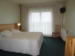 een slaapkamer met een bed, een stoel en een raam bij Hotel Akelarre in Santiago de Compostela