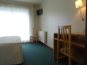 een slaapkamer met een bed, een bureau en een raam bij Hotel Akelarre in Santiago de Compostela