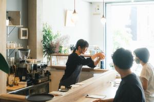 Eine Frau, die in einer Küche steht und Essen zubereitet. in der Unterkunft Okazaki Micro Hotel ANGLE in Okazaki