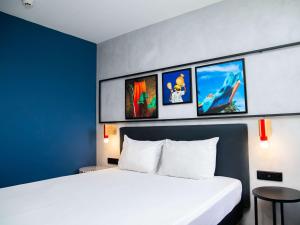 um quarto de hotel com duas camas e fotografias na parede em Ibis Styles Abidjan Plateau em Abidjan