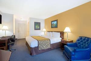 a hotel room with a bed and a desk and a chair at Super 8 by Wyndham Oroville in Oroville