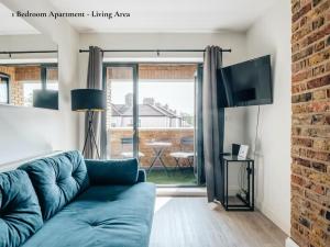 uma sala de estar com um sofá azul e uma grande janela em Lux Bermondsey Apartments Near Tower Bridge em Londres
