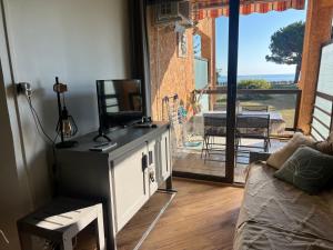 a living room with a couch and a television and a balcony at Appartement n 79 Moriani plage in Santa-Lucia-di-Moriani