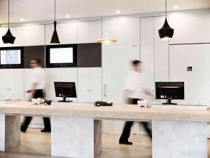 a reception desk with people walking in a room at ibis Novo Hamburgo in Novo Hamburgo