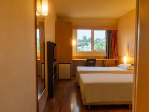 a hotel room with two beds and a window at ibis Novo Hamburgo in Novo Hamburgo