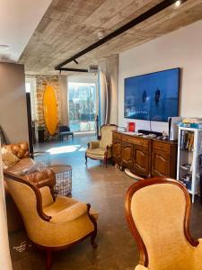 a living room with chairs and a large screen tv at Zarautz Surf House in Zarautz