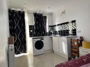 a kitchen with a washing machine in a room at Iron Mill Lane studio in Slades Green