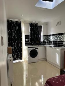 a kitchen with a washer and dryer in a room at Iron Mill Lane studio in Slades Green