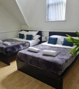 two beds in a room with blue and white at Tudors eSuites Budget Studio Apartment in Birmingham
