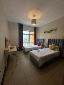 ein Hotelzimmer mit 2 Betten, einem Schreibtisch und einem Fenster in der Unterkunft شقق فخامة المارينا Grandeur Marina Apartments in King Abdullah Economic City