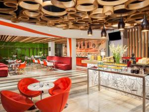 a restaurant with red chairs and tables and a ceiling at ibis Yogyakarta Adi Sucipto in Yogyakarta